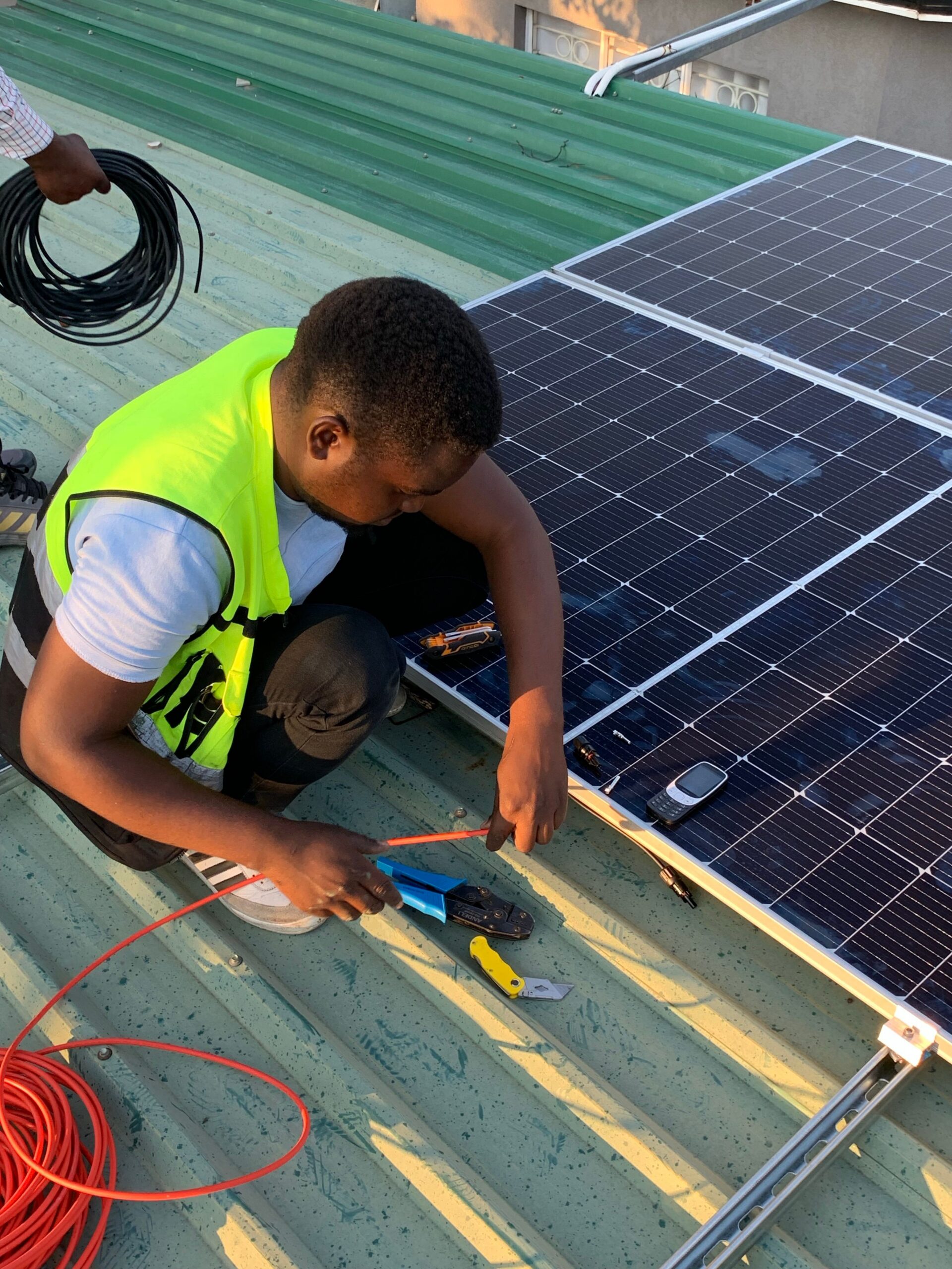 Technicien africain installant des panneaux solaires sur un toit