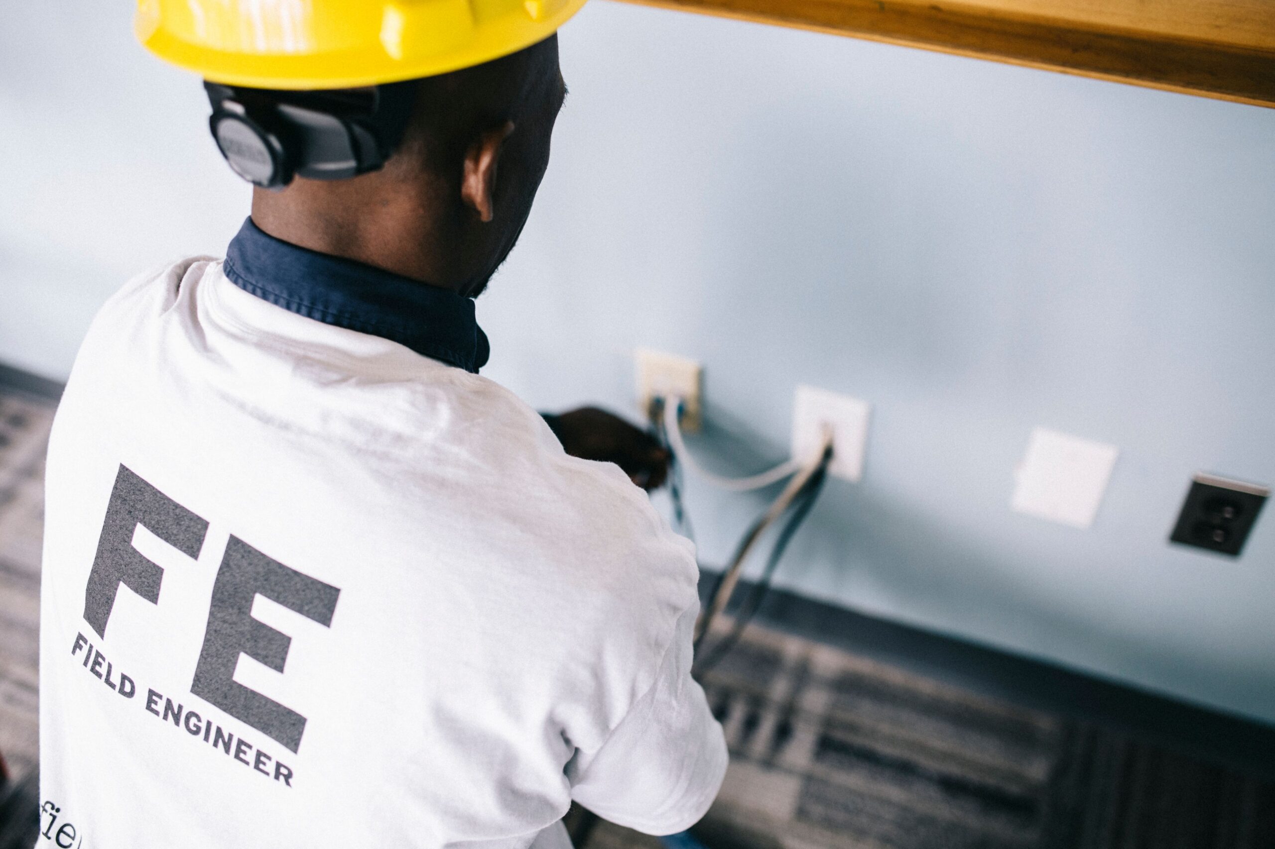 Technicien africain reparant des prises electriques avec casque de chantier